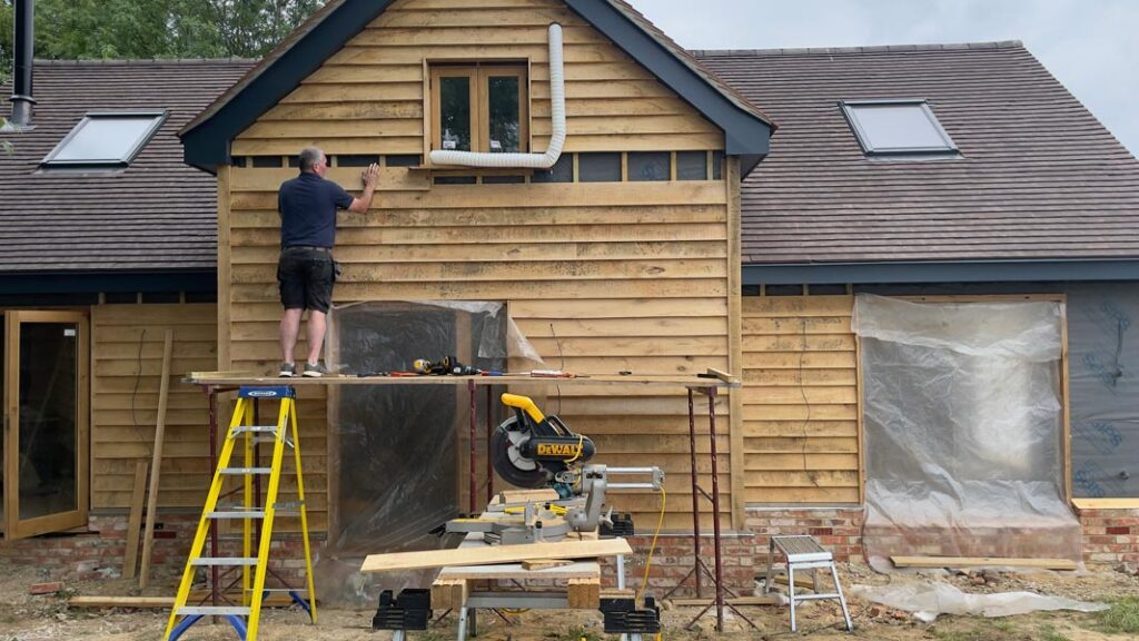 A man on a ladder working on a house during new build construction.