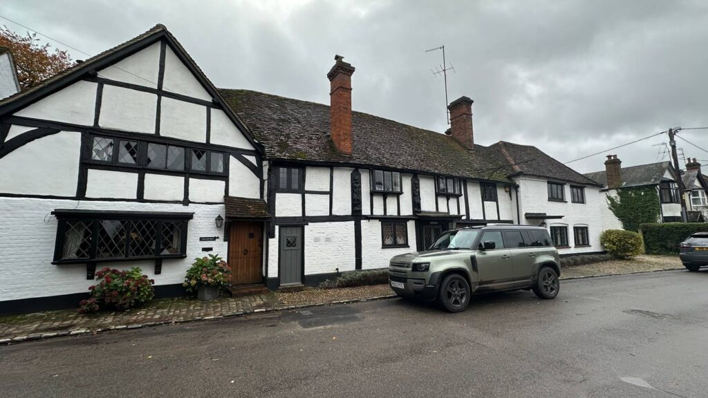 A parked car in front of an old historic house in England.