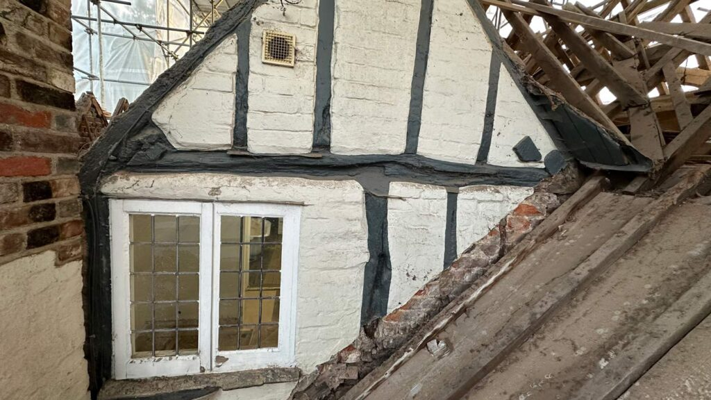 The image shows a house with its roof completely removed, revealing the interior. This relates to building conservation.